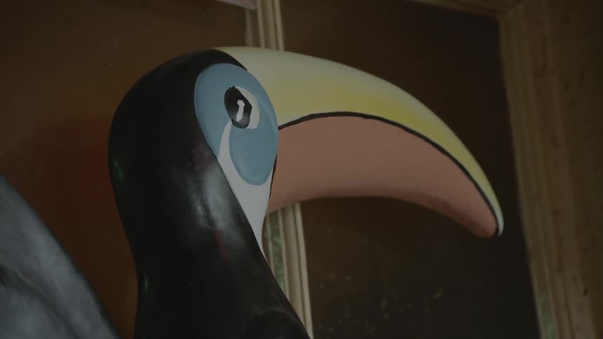 A statue of a toucan sits inside a room