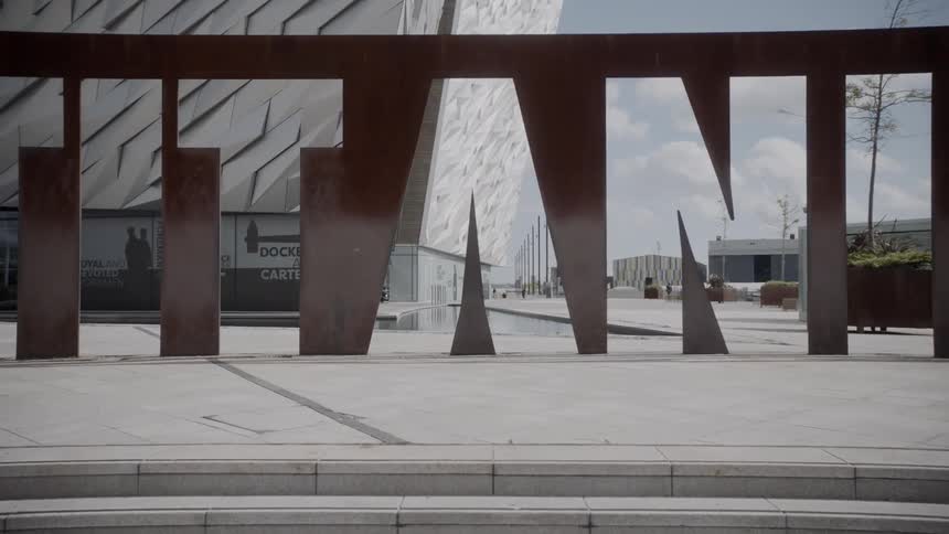 Large marquee sculpture spelling titanic in front of geometric building