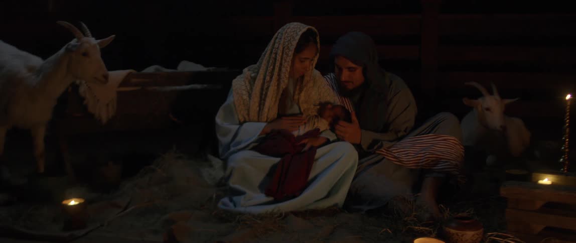 A man and a woman in a stable holding a baby