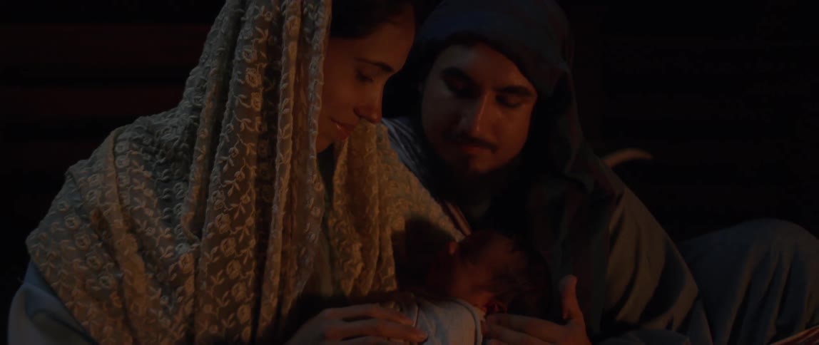 A mother and father lovingly hold their newborn baby at night