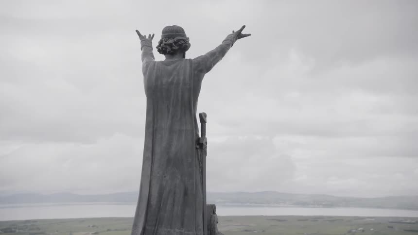 A sculpture on a hill overlooking the countryside on a cloudy day