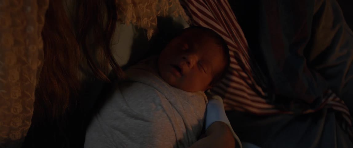 A black baby sleeps in a persons arms