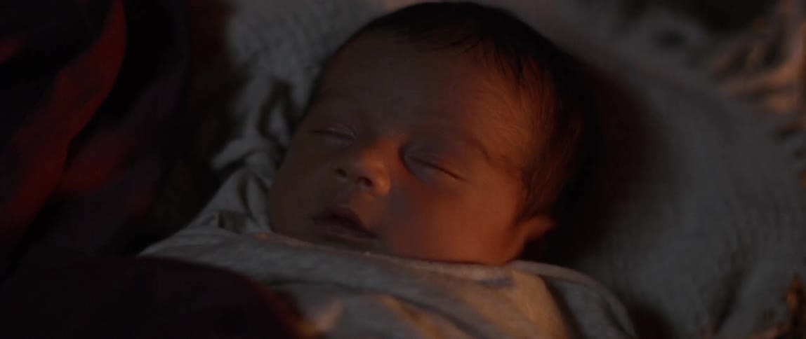 Baby sleeps peacefully while the face is illuminated by fire at night