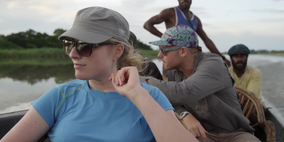 A group of men and women view the land while traveling in a boat