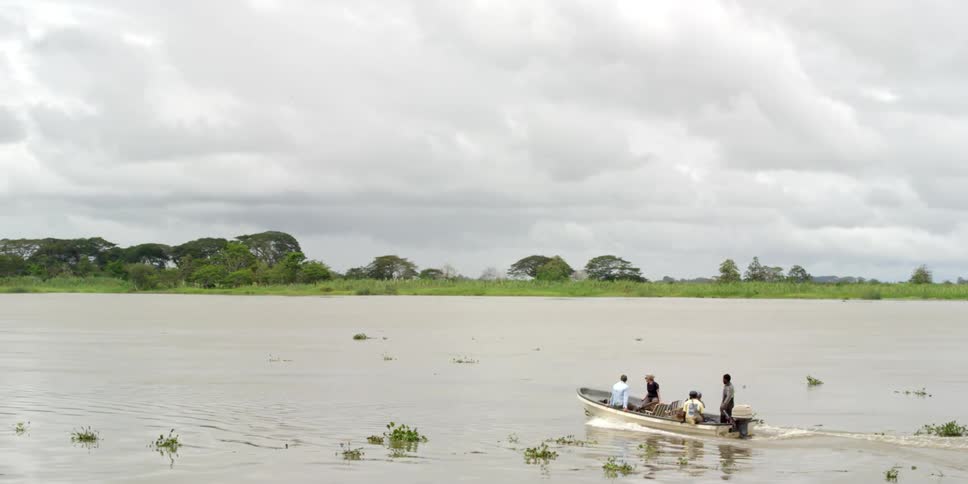 A boat with four men in it travels down across a body of water