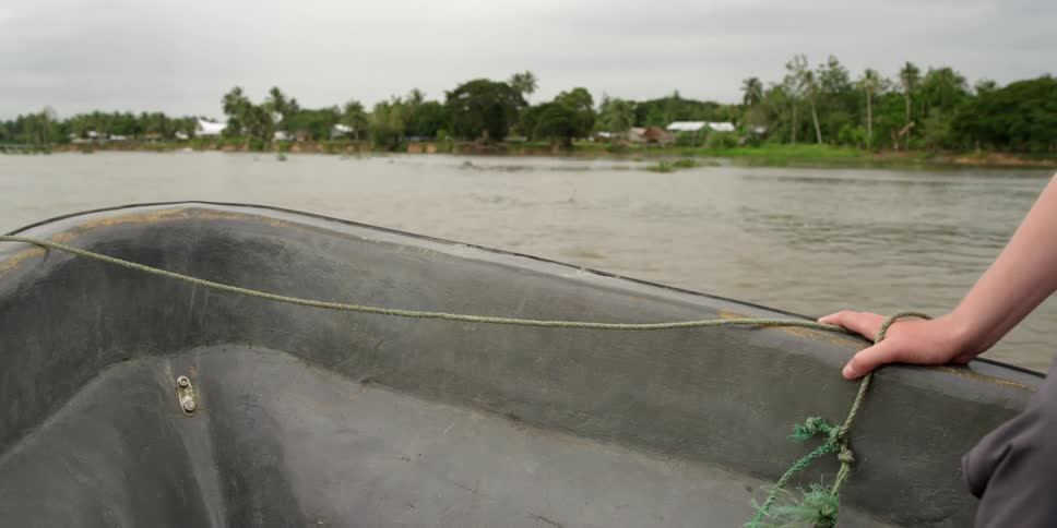 A boat travels across a river on a cloudy day