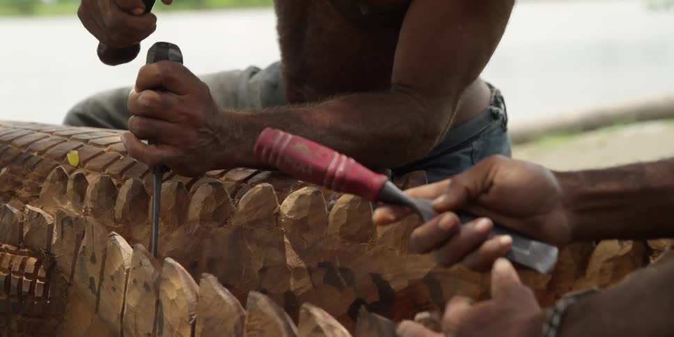A man chisels away at a wood carving