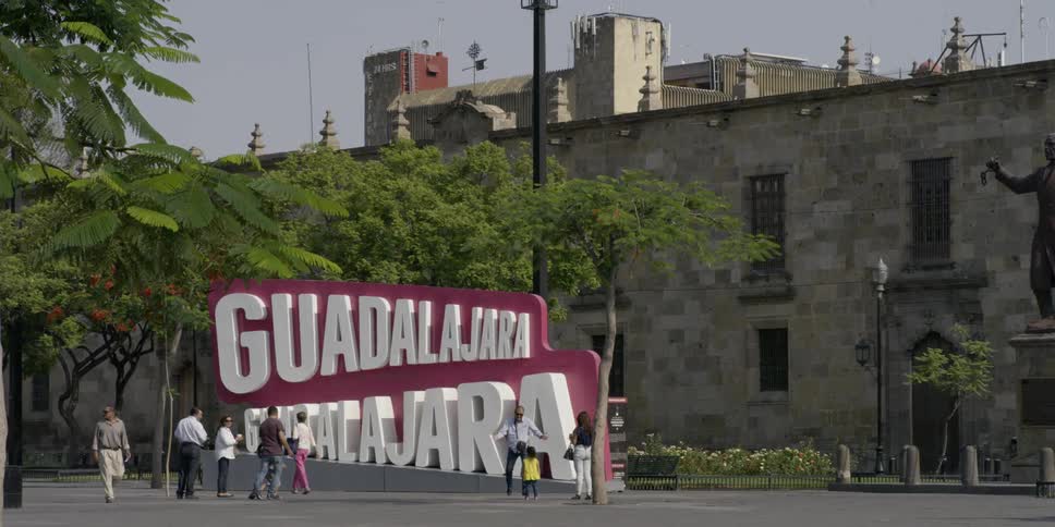 People look at a large tourist sign with the city name on it