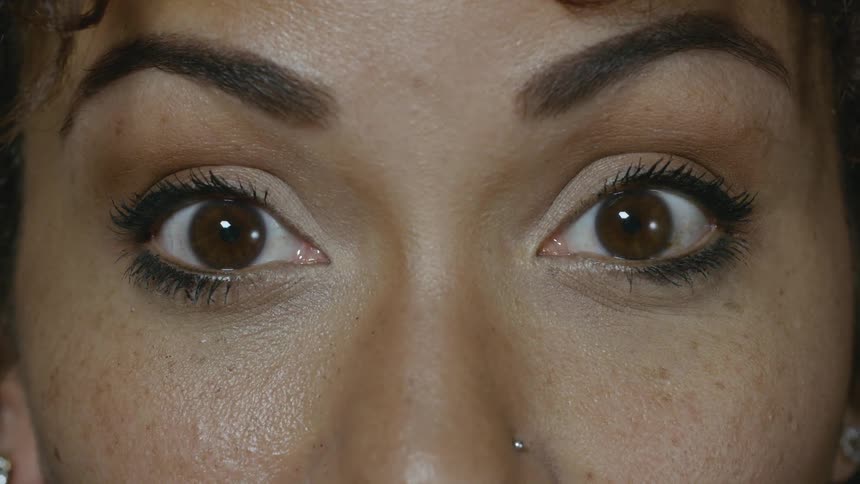 A female drops her hands from her face and opens her eyes wide