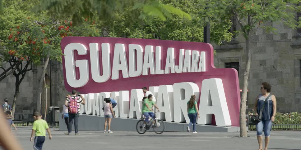A large amount of people walk by a large tourist sign