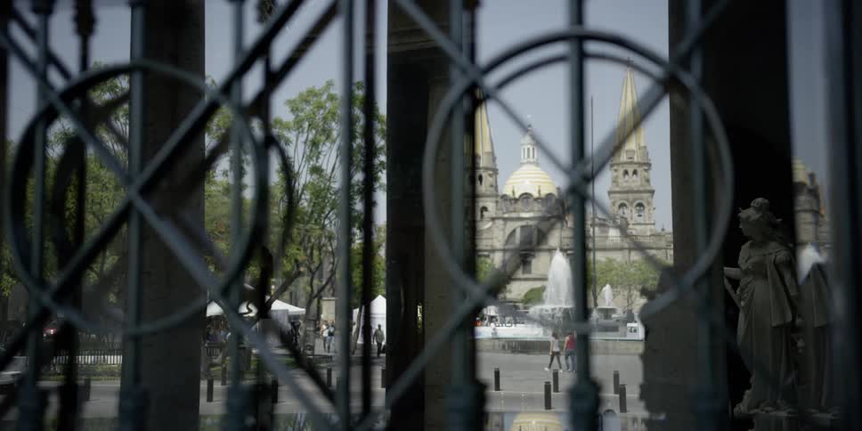 An old church and fountain as seen through a mirrored window from across the street