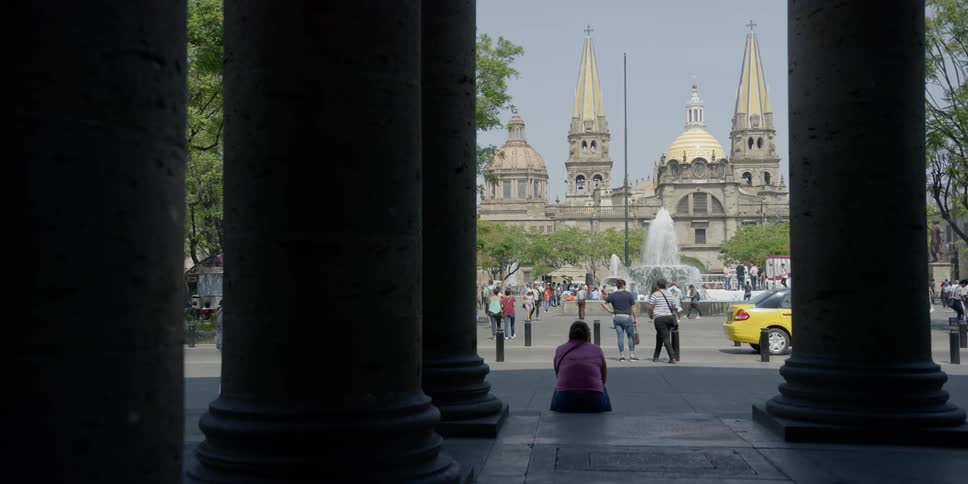 People walk around a fountain in front of a large church