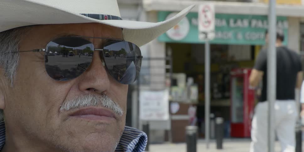 A man in a cowboy hat and sunglasses standing in front of a store