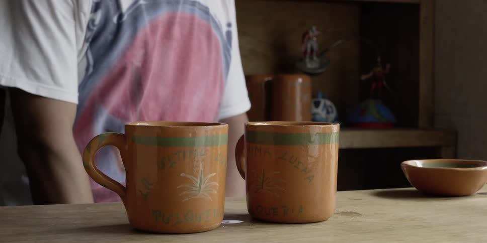 A person pours liquid into mugs