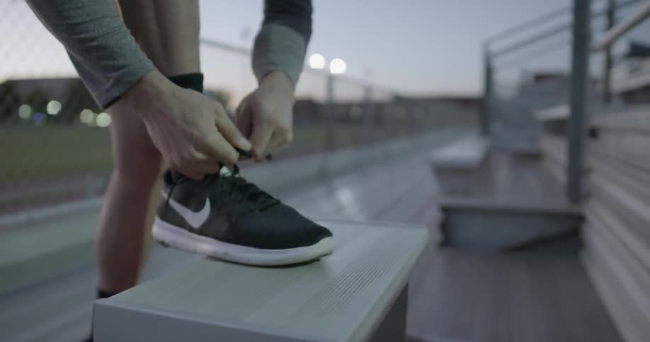 A white man ties his shoe while balancing his foot on a step