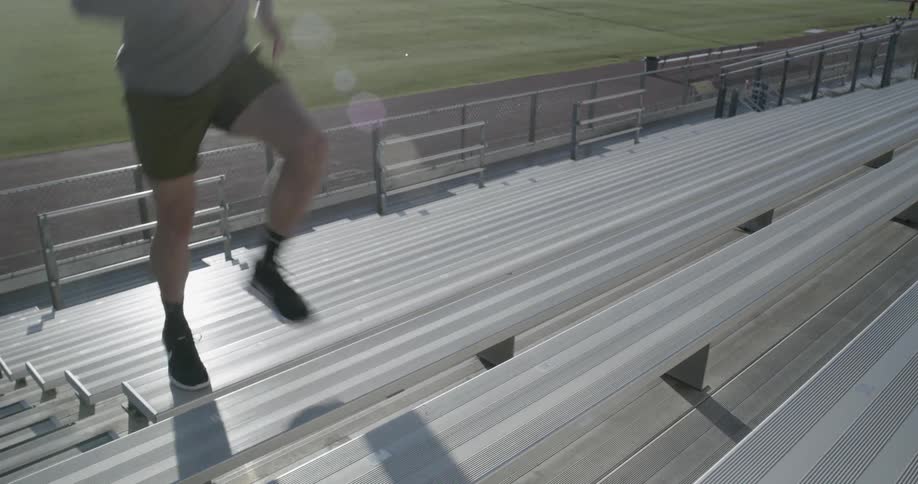 A male caucasian running up bleachers outside