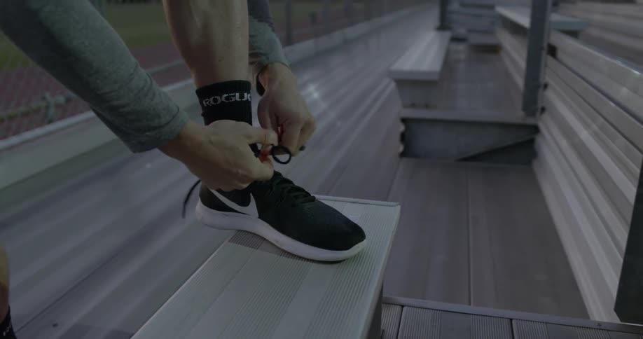 A man is tying his shoes outdoors