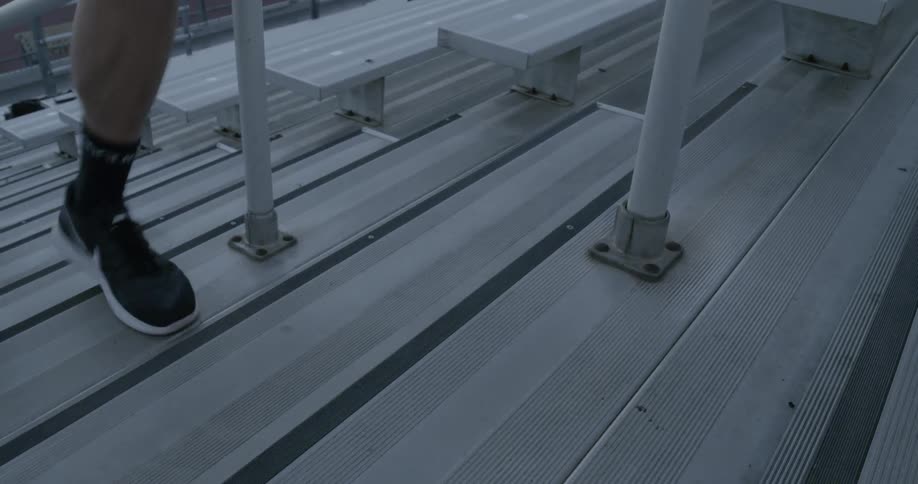 A man runs up the bleachers wearing gym shoes