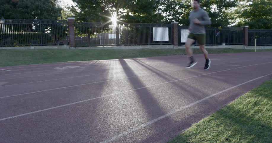 A white man runs along an outdoor race track
