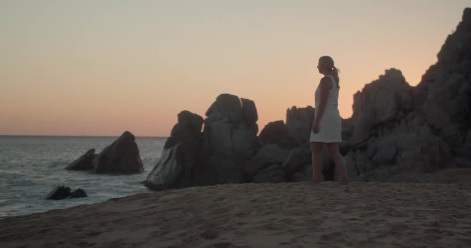 A young woman walks along the beach towards the water