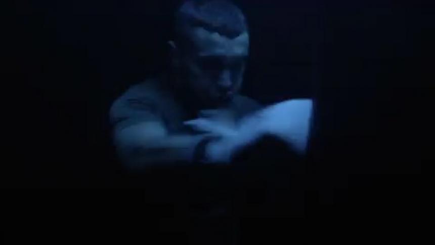 A man with boxing gloves punching a heavy bag with flashing lights
