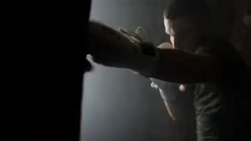 Two men wearing boxing gloves are boxing in the dark with strobe lights flickering
