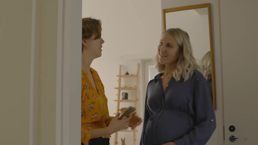 A brunette woman shows a blonde woman her smartphone