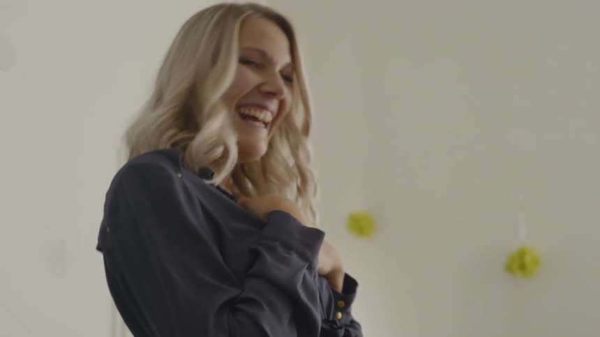 A woman puts a string around a pregnant womans belly as she laughs