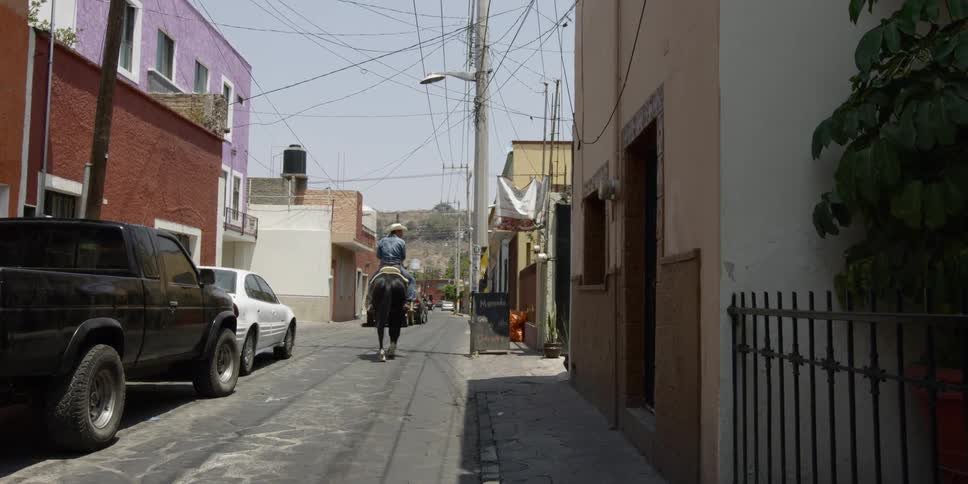 A man riding a horse down an alley