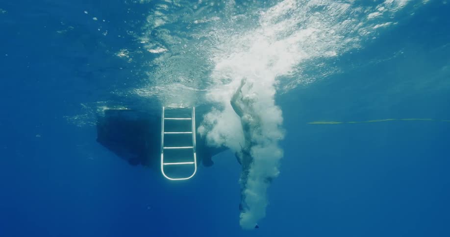A woman jumps off the edge of a boat and into the water