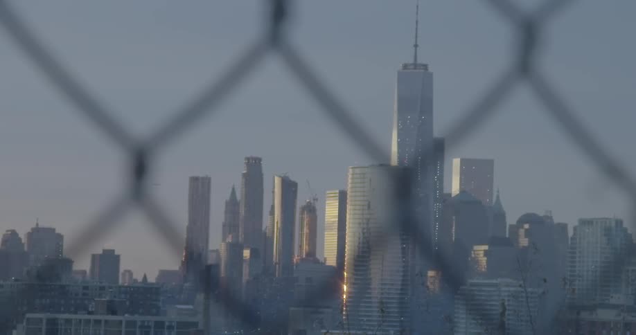 Buildings and skyscrapers seen through a chain link fence