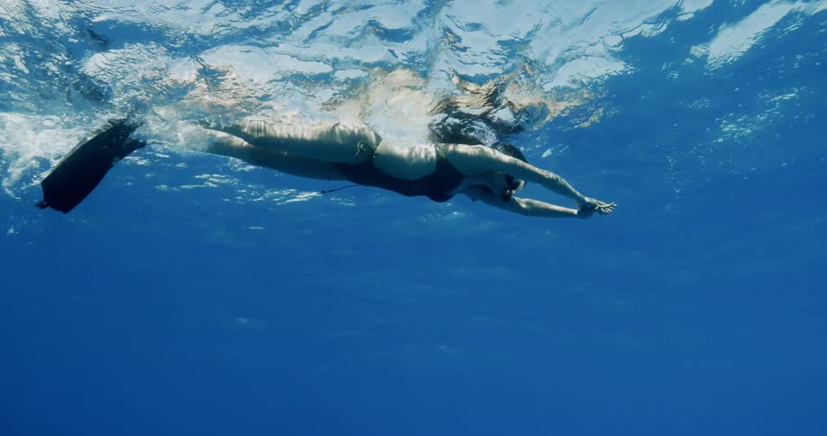 A woman with flippers and a snorkel swimming underwater
