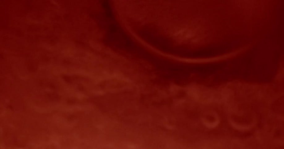 Red liquid splashing onto a surface and creating bubbles