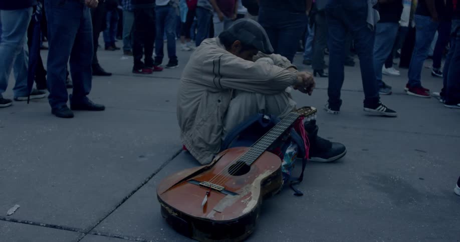 A man with a guitar sitting on the ground