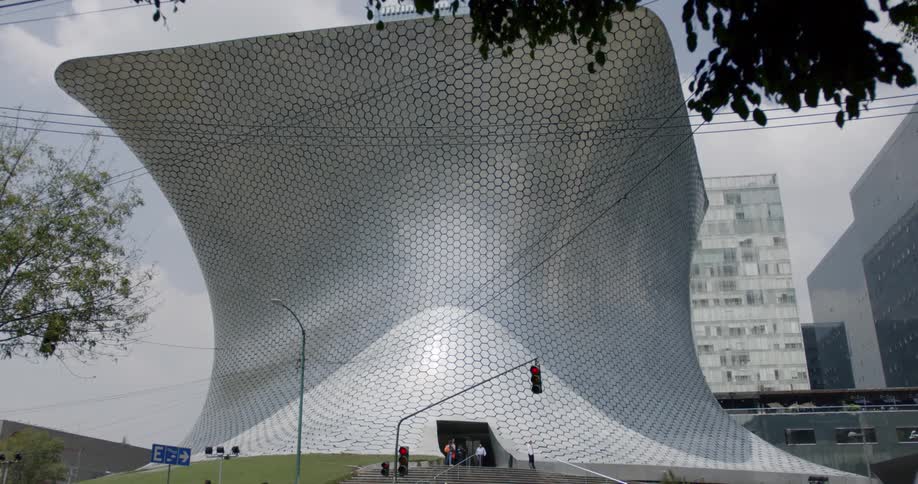 A modern structure sits on a small hill in a city