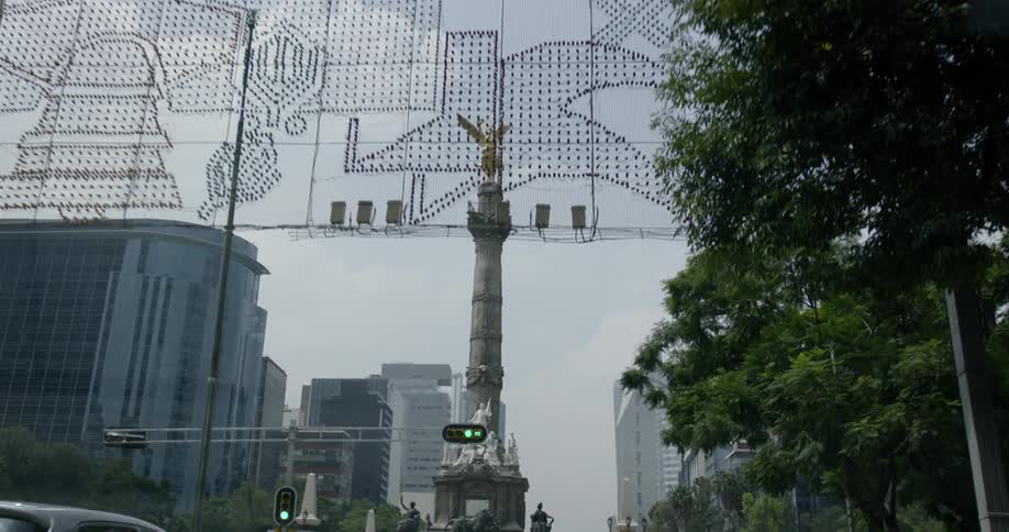 Overhead light display and angel topped pedestal in city