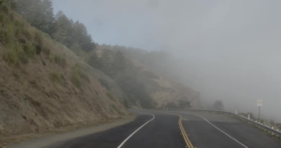 A road next to a cliff with the sky and trees in the background