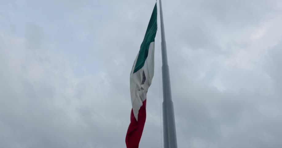 Mexican flagrippling in the breeze under a cloudy sky