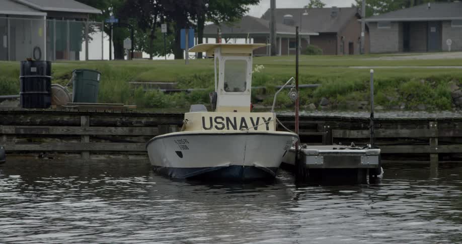 A us navy boat tied to a small dock by buildings