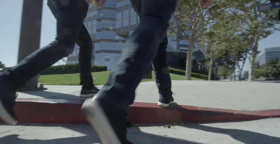 Two people walk across a crosswalk and onto a sidewalk