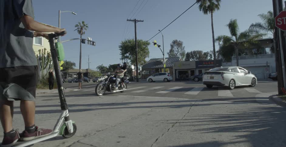 A person rides a scooter down the street