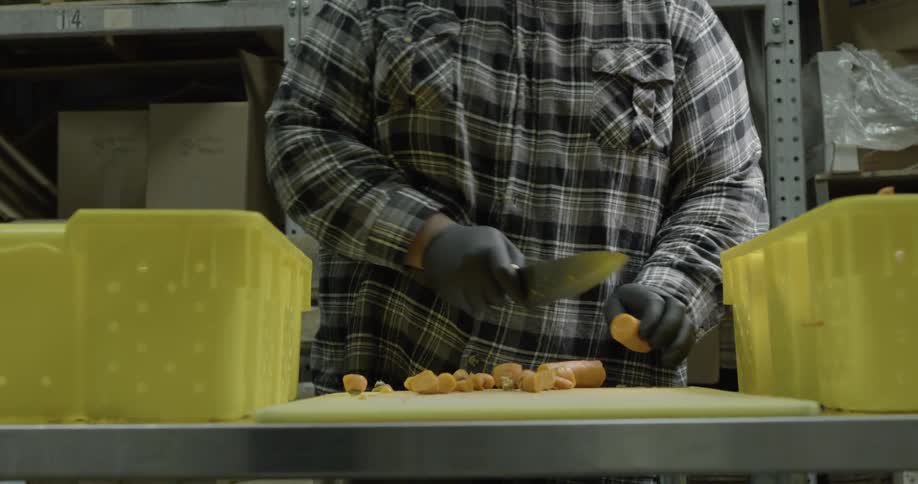 A man chops up carrots on a cutting board