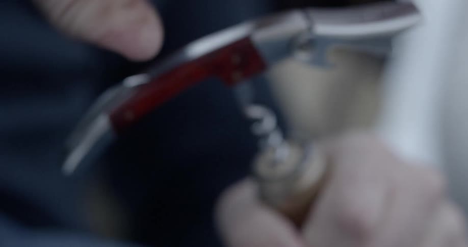 Close up of hands using a corkscrew on a cork