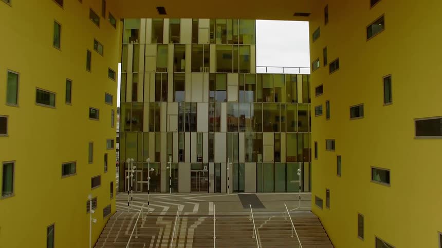 Yellow walls and randomly placed windows over steps on a glass front city building