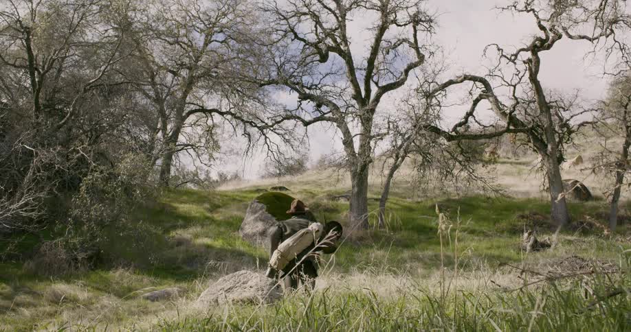 A man carries camping equipment over the field