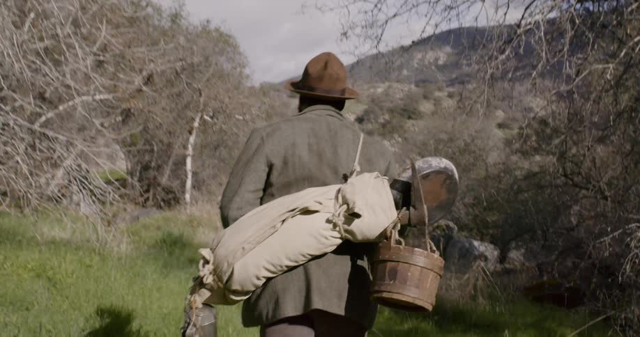 A man walking with mining supplies on his back