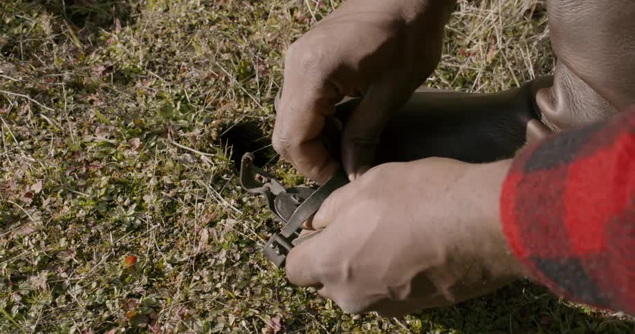 A black male setting a trap on the grass