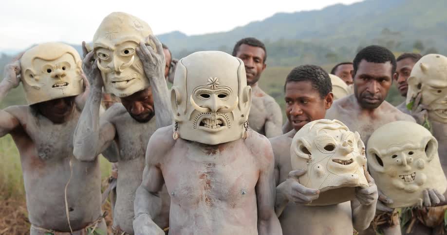 Tribal men with body paint and face masks stand outside
