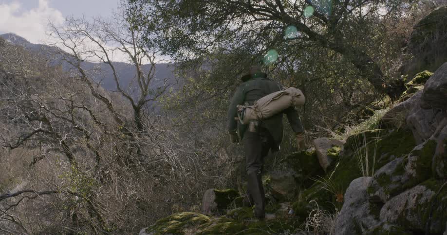 A man is hiking as he climbs around the rocks on the hill