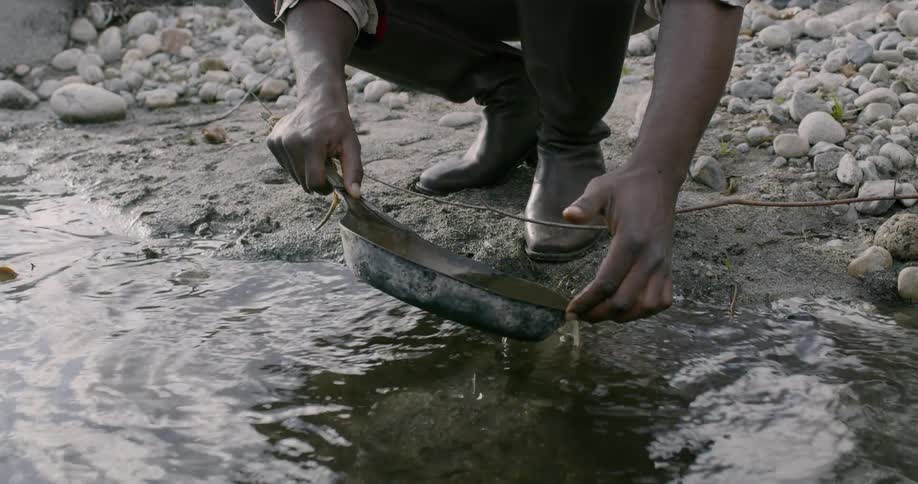 A man near a river panning for gold in the daytime
